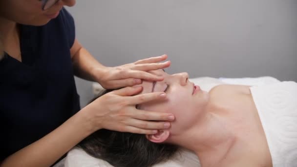 Masáž - mladá žena tlačí na tvář své klientky — Stock video