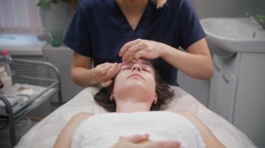 Masaj seansı - genç kadın müşterilerinin yüzüne akupres yapıyor