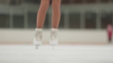 Küçük kız artistik patinajcı buz pistinde durur.