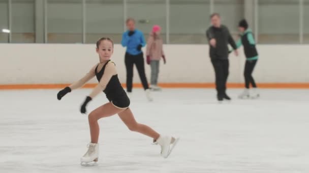 Menina figura patinadora em preto e amarelo traje patinação na pista pública — Vídeo de Stock