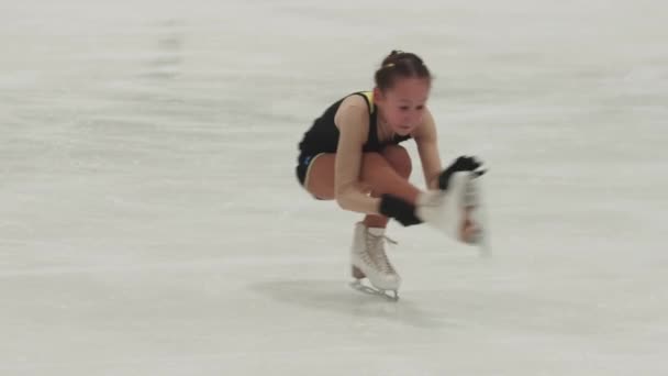 Holčička krasobruslařka v černém a žlutém kostýmu spinning na veřejném kluzišti — Stock video