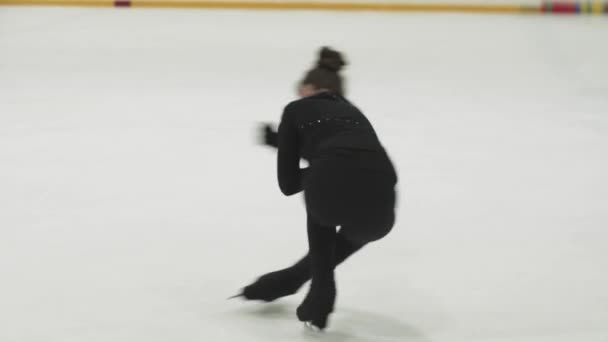 Little girl figure skater in black training costume spinning around on the rink — Stock Video