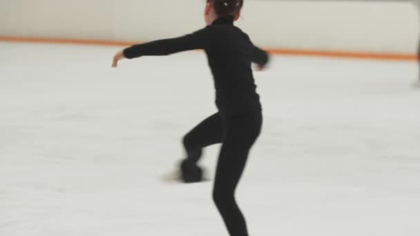 Little girl figure skater in black training costume spinning around on the public rink — Stock Video