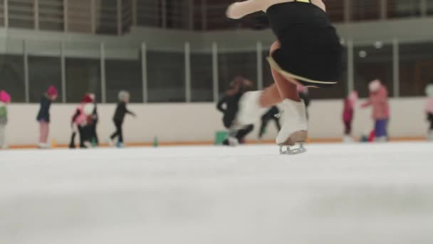 Uma garota patinadora artística em traje de treinamento girando na pista pública — Vídeo de Stock