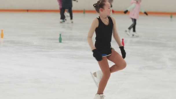 Petite fille patineuse artistique à l'entraînement noir et jaune costume de patinage et de tourner autour sur la patinoire publique — Video