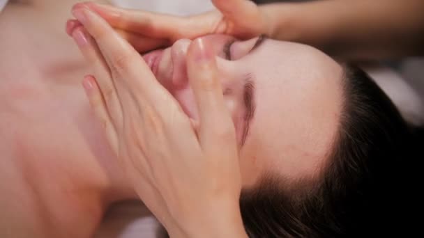 Sessão de massagem - jovem mulher deslizando os dedos nas bochechas de seu cliente — Vídeo de Stock