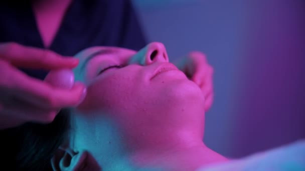Massaggio sessione - giovane donna utilizzando piccole pietre di giada sul viso del suo cliente femminile — Video Stock
