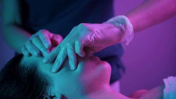 Massage session - kvinna terapeut massera ansiktet på sin kvinnliga klient med hjälp av fingrarna - lila belysning — Stockvideo