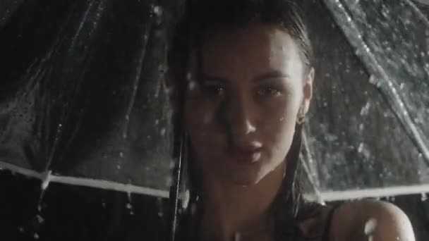 Yağmurun altında şemsiye tutan ıslak, genç bir kadın. — Stok video