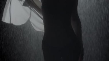 Güzel vücutlu seksi genç bir kadın yağmurun altında ıslak gömleğiyle oynuyor.