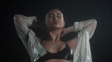 Güzel vücutlu, yağmurun altında ıslak tişört giyen seksi genç bir kadın.