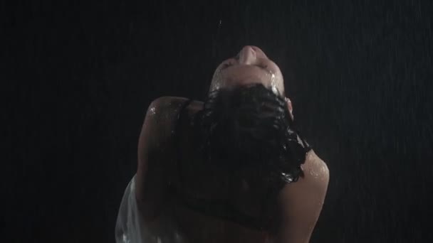 Güzel vücutlu, yağmurun altında kavisli, ıslak tişörtlü seksi genç bir kadın. — Stok video