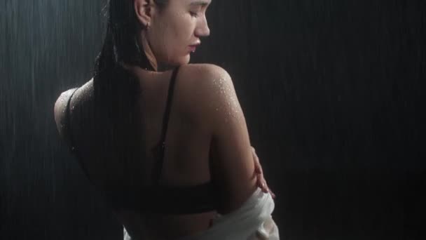 Gorąca młoda kobieta z ładnym ciałem siedzi na kolanach i cieszy się deszczem — Wideo stockowe