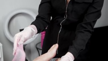 Ağda işlemi - usta müşterisinin kadın bacaklarını pembe bantlarla cilalıyor