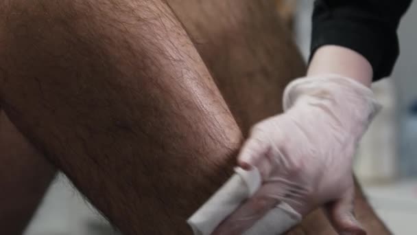 El maestro de la depilación preparando la pierna de su cliente masculino para depilarse — Vídeo de stock