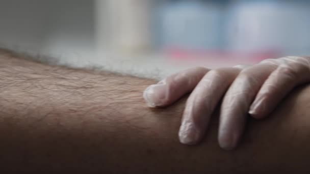 Wachsbehandlung - haariges Bein des männlichen Klienten und der Meister beginnt, einen Wachsstreifen aufzutragen — Stockvideo