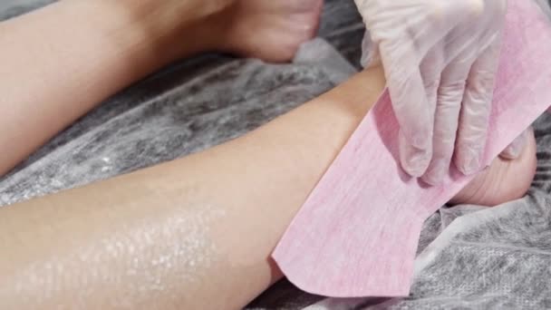Ağda prosedürü - usta müşterisinin kadın bacaklarını şerit kullanarak cilalıyor — Stok video