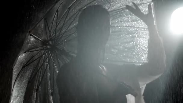 雨の下に立つ若い女性のシルエットと傘を持っている — ストック動画