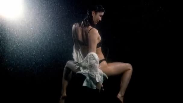 Seksi vücutlu seksi genç bir kadın yağmurun altında sandalyede oturuyor. — Stok video