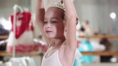 Parlak mavi gözlü küçük kız balerin yavaşça kendi etrafında dönüyor.