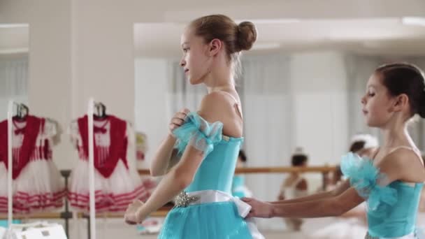 Gadis balerina kecil memperbaiki rambutnya dan temannya membantunya dengan kostumnya — Stok Video