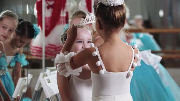 Маленька дівчинка балерина кладе тіару на голову свого друга іншу балерину — стокове відео