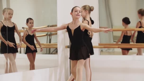 Drie balletmeisjes voor een spiegel - een van hen begint te dansen op de camera — Stockvideo