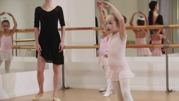 Drie kleine ballet meisjes trainen met hun vrouwelijke coach in de spiegel studio — Stockvideo