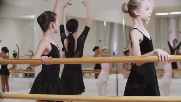 Группа девчонок тренирует балет в зеркальной студии с тренером — стоковое видео