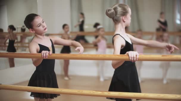 Ομάδα μικρών κοριτσιών που εκπαιδεύουν μπαλέτο στο στούντιο καθρέφτη με μια γυναίκα γυμνάστρια — Αρχείο Βίντεο
