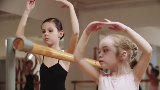 Две девушки-балерины тренируются в студии возле стенда — стоковое видео