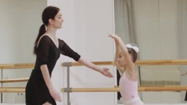 Bale eğitimi. Ayna stüdyosunda dans eden küçük bir kız balerin. Antrenör onu izliyor.