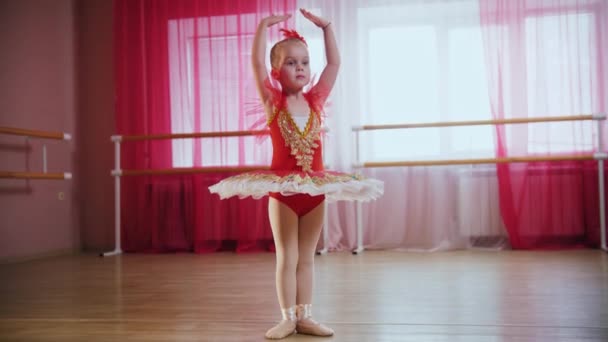 Ein kleines Mädchen im roten Kleid steht in Ballettposition — Stockvideo