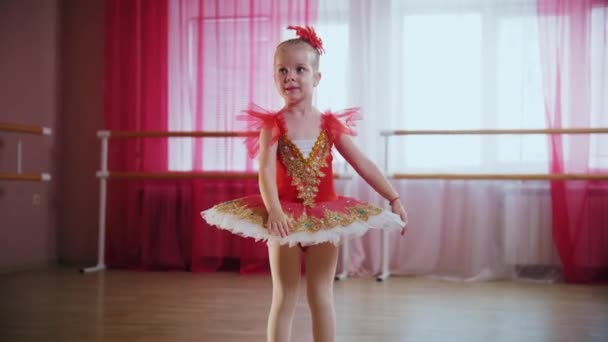 Una niña en vestido rojo mostrando movimientos de ballet y sonriendo — Vídeos de Stock