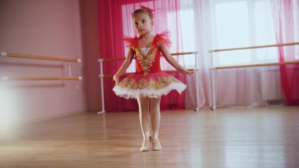 Een klein meisje in rode jurk draait om zich heen — Stockvideo