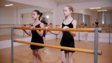 Bale eğitimi. Ayna stüdyosunda bale eğitimi alan bir grup kız. Diğerlerinden farklı olarak iki kız.