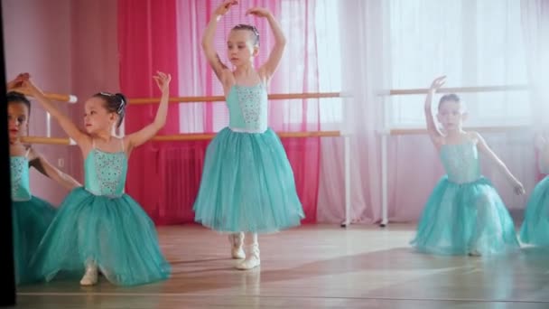 Маленькие балетницы в голубых платьях готовятся к тренировкам в студии — стоковое видео