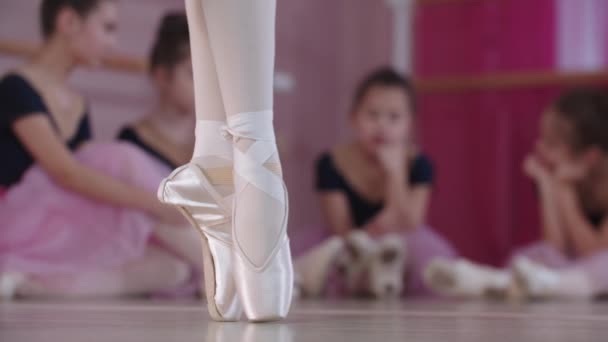 Entrenamiento de ballet: bailarinas con hermosos vestidos sentadas en el suelo y una de ellas bailando en primer plano — Vídeos de Stock
