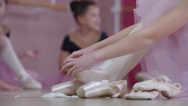 Treinamento de balé - meninas em belos vestidos sentados no chão e um deles colocando sapatos pontiagudos — Vídeo de Stock