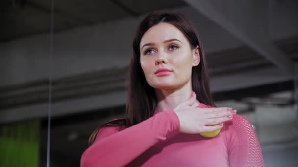 Joven mujer deportiva en traje rosa rodando una pelota de tenis en su pecho — Vídeo de stock