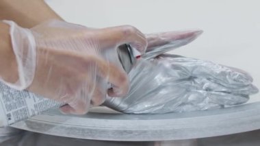 Tablonun ahşap çerçevesine gümüş boya püskürtüyor.