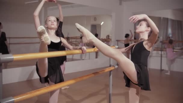 Обучение балету - студенты-балерины, растянувшиеся у стенда с помощью тренера — стоковое видео