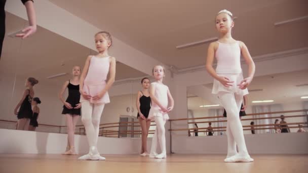Εκπαίδευση μπαλέτου - ομάδα μικρών κοριτσιών μπαλαρίνας κάνουν σύγχρονες κινήσεις στο στούντιο — Αρχείο Βίντεο
