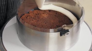 Şekerci kekin üzerine vanilyalı krema sıkıyor.