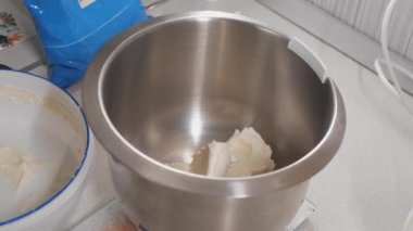 Pasta şefi tencereye krem peynir koyar.