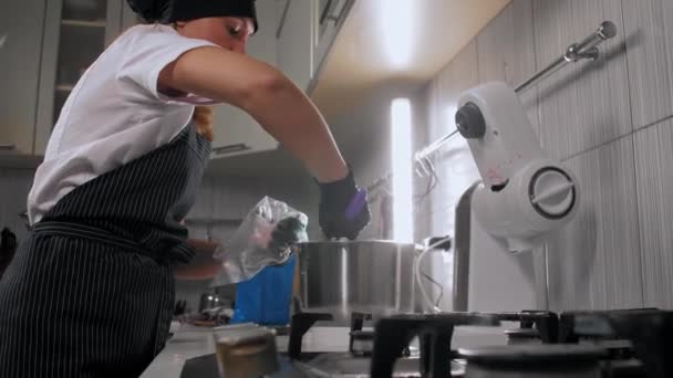 한 여자 페이스트리 요리사가 분홍 케이크 크림으로 만든 과자를 포장하고 있다 — 비디오
