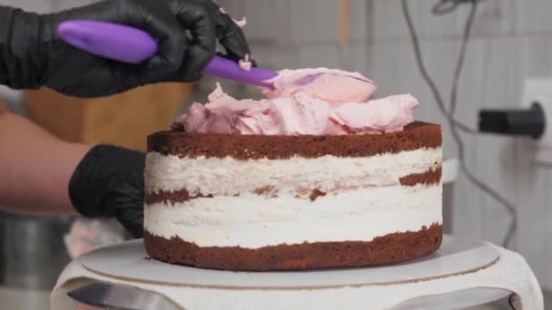 O chef de pastelaria aplica creme rosa em cima de um bolo em branco — Vídeo de Stock