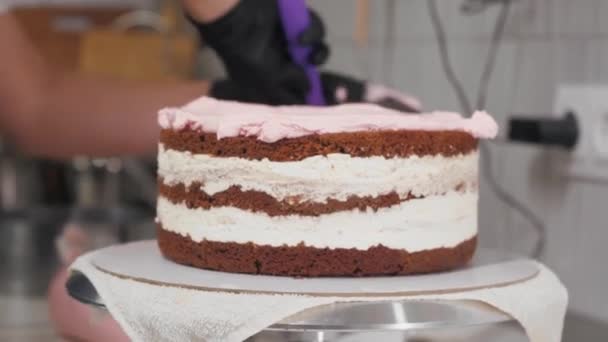 A cukrász rózsaszín édes krémet tesz a torta üres tetejére. — Stock videók