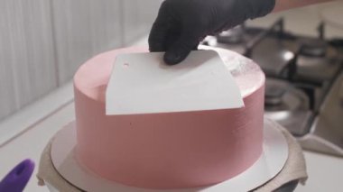 Büyük bir spatula kullanarak pastanın üst yüzeyini düzleştirir.