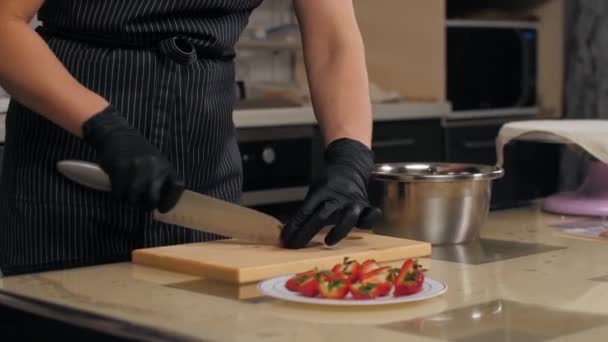 Banketbakker snijdt verse aardbeien in helften voor het versieren van taart — Stockvideo